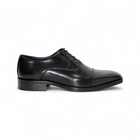 The Firmani Owen Black by Firmani is a genuine leather oxford dress shoe with a cap toe, laces, and low stacked heel, shown in profile on a white background—an icon of timeless style.