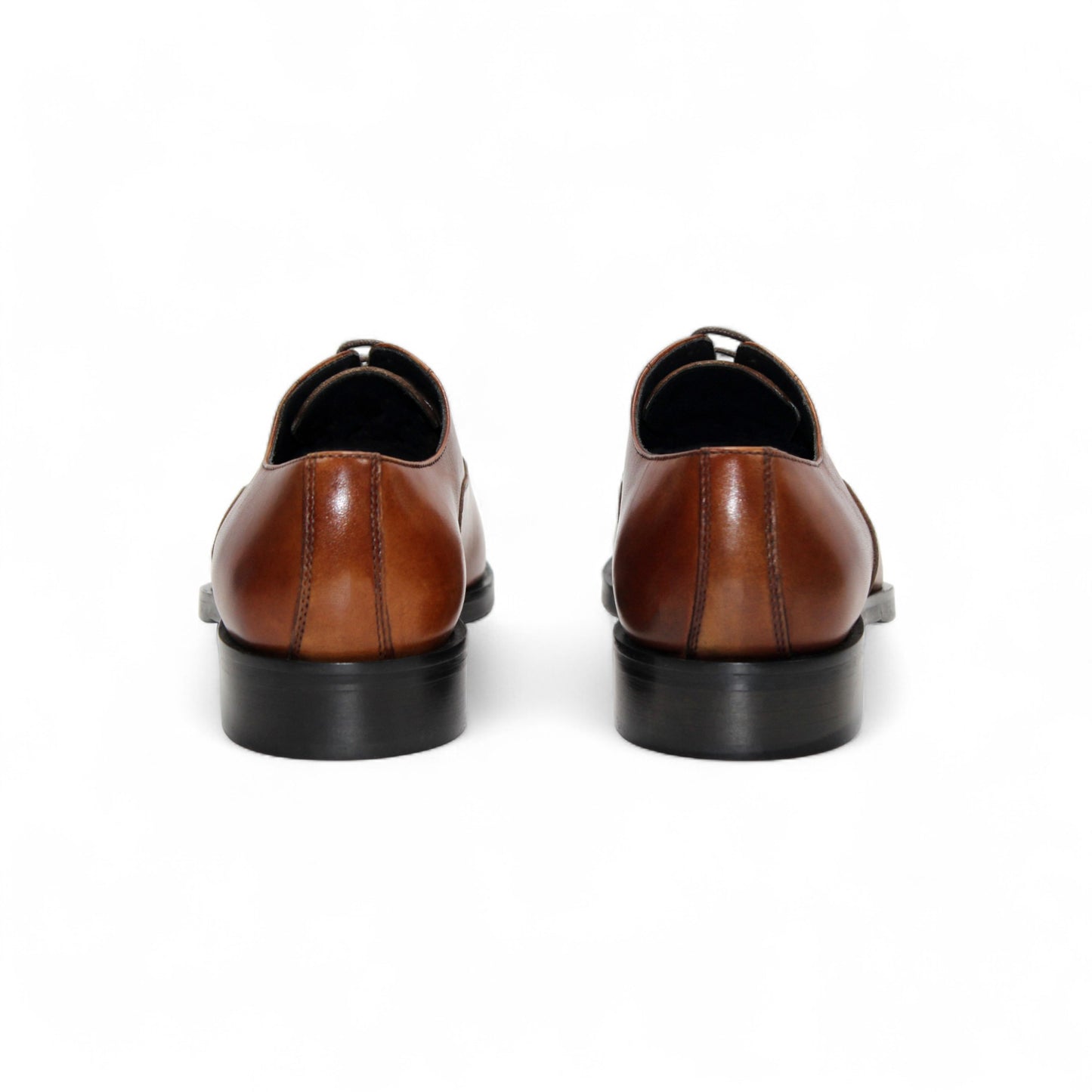 The Firmani Owen Cognac by Firmani is a brown genuine leather oxford dress shoe with a black sole, shown in a side view on a plain white background—ideal for timeless style enthusiasts.