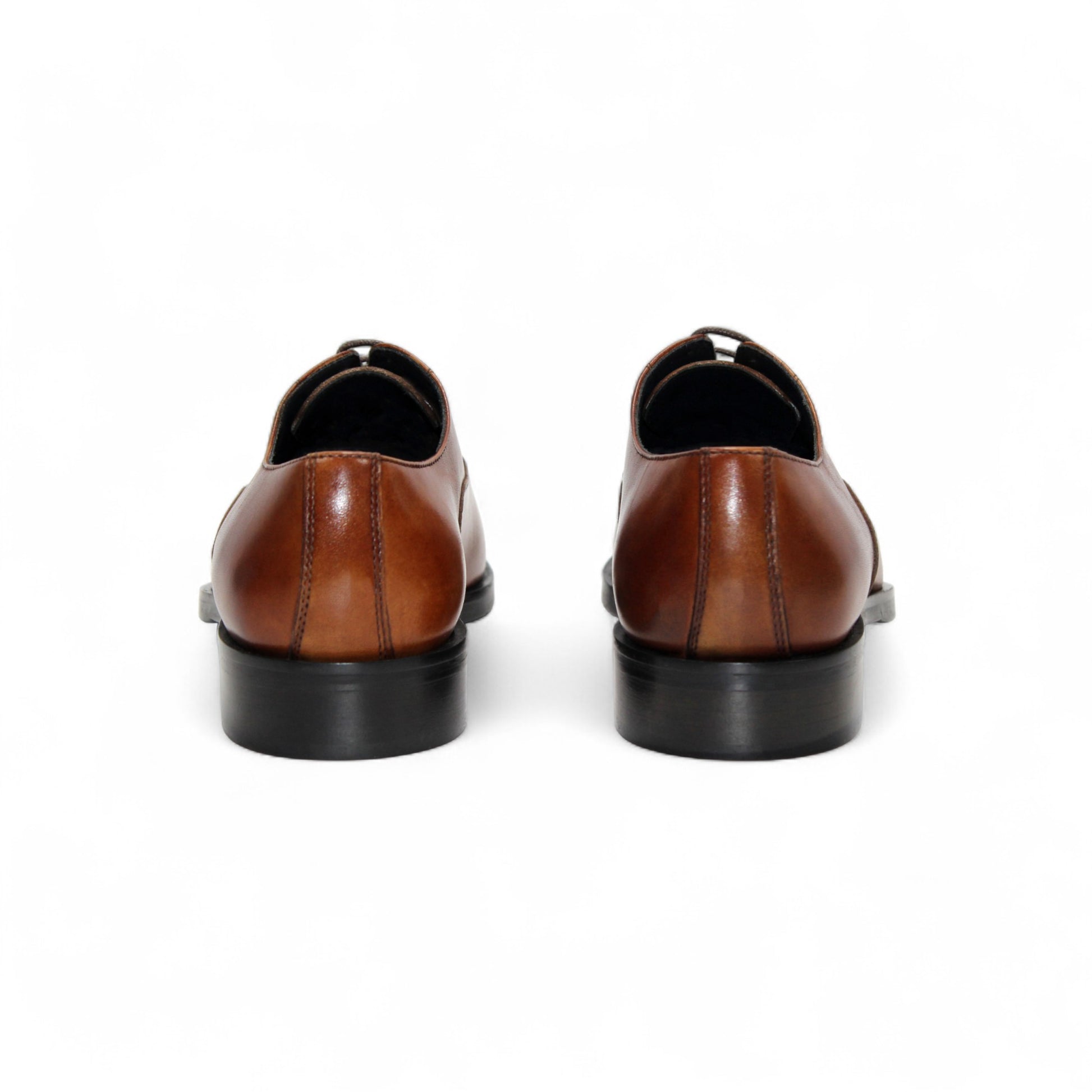 The Firmani Owen Cognac by Firmani is a brown genuine leather oxford dress shoe with a black sole, shown in a side view on a plain white background—ideal for timeless style enthusiasts.
