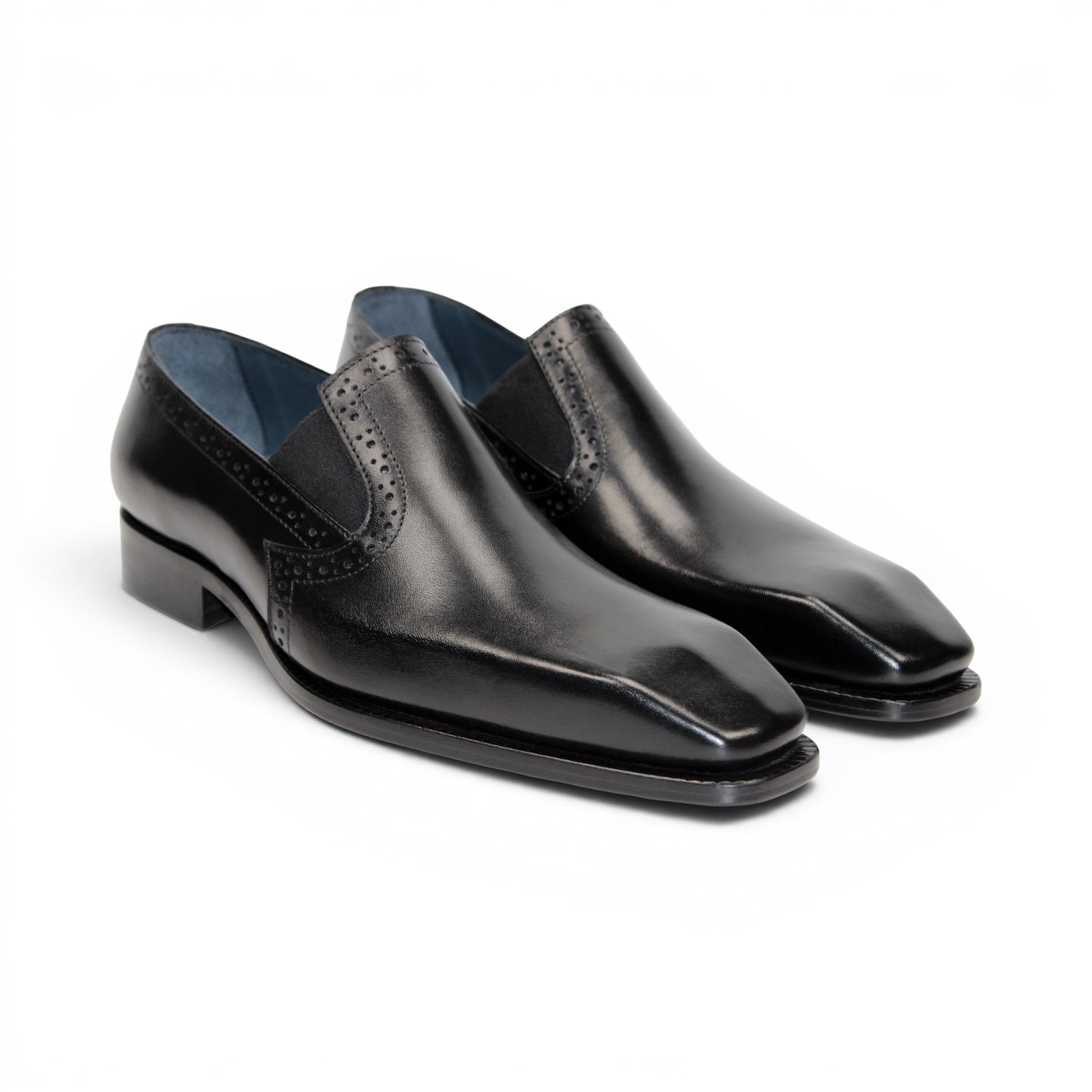 The Duca Di Matiste Duca Paliano Black is an Italian-made slip-on dress shoe in premium black calf leather, featuring a low heel and decorative perforations, shown in profile for timeless style.
