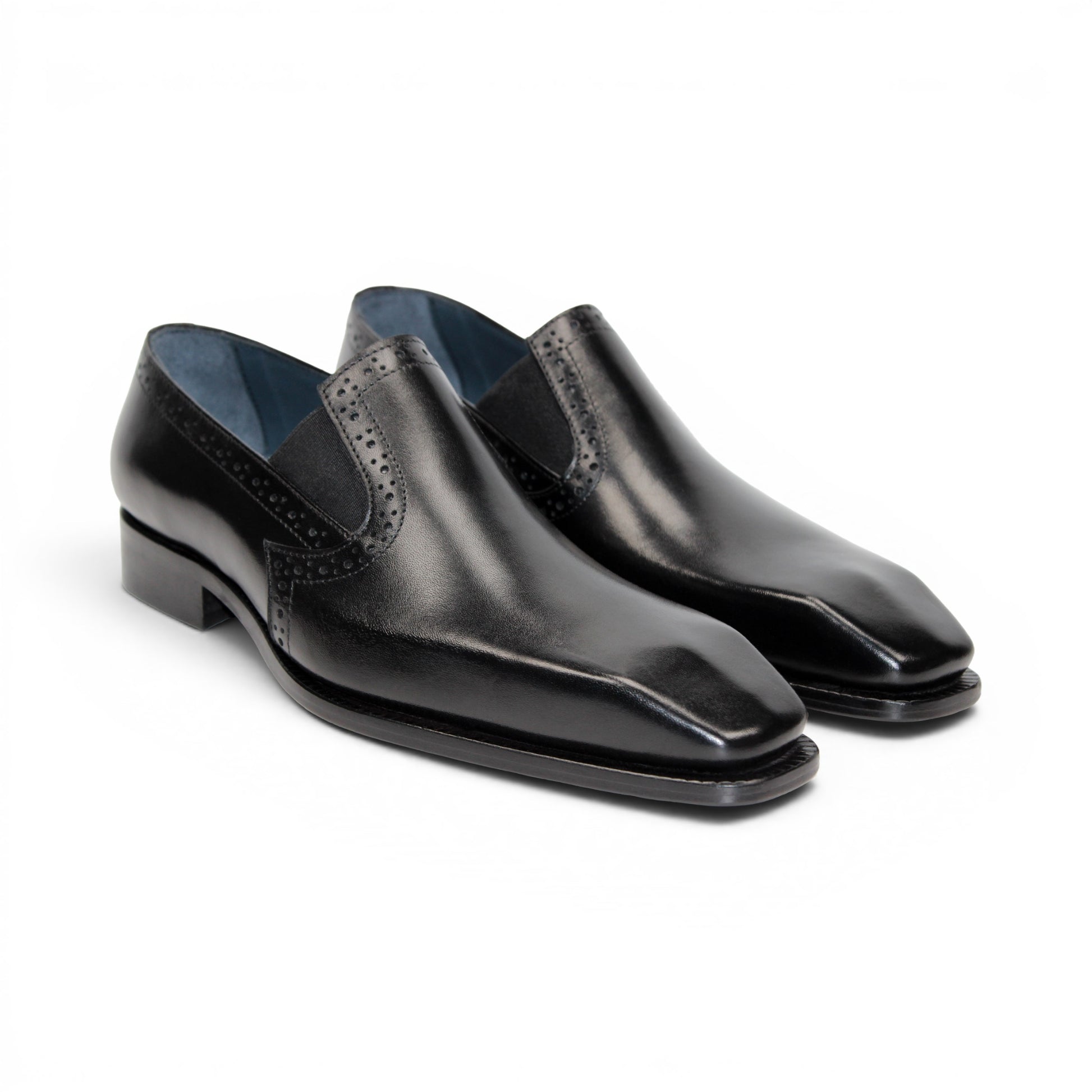 The Duca Di Matiste Duca Paliano Black is an Italian-made slip-on dress shoe in premium black calf leather, featuring a low heel and decorative perforations, shown in profile for timeless style.