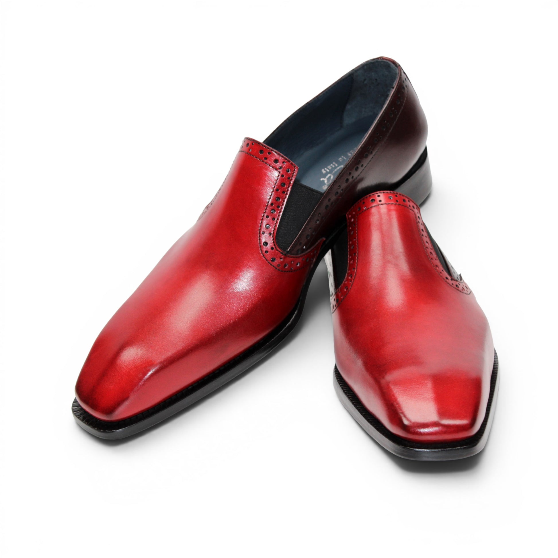 The Duca Di Matiste Duca Paliano Red/Burgundy is a men’s slip-on dress shoe in fine calf leather, featuring a red and dark brown upper with decorative perforations and a black low heel—Italian-made timeless style.