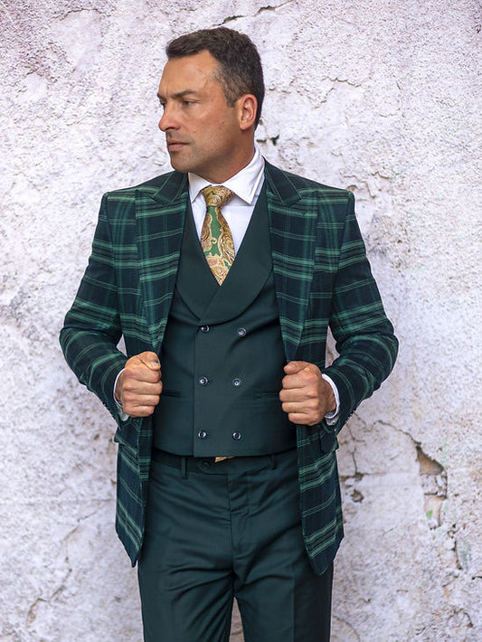 A man wears the Manzini PARIS-1 Men's 3-Piece Tailored Fit Plaid Business Suit in forest green with a patterned tie, standing against a textured light wall, looking to the side while holding his jacket.