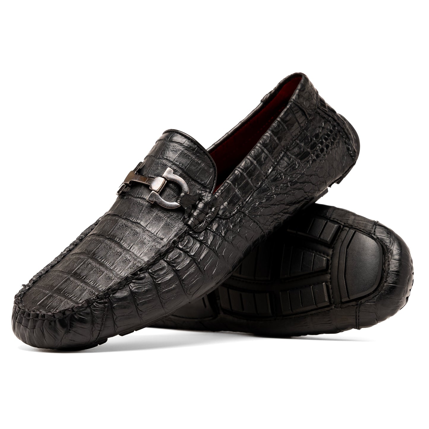 The Marco Di Milano Parma Black is a luxury caiman belly loafer featuring black crocodile-textured leather, metal buckle accents, and rubber soles, with one men’s driving shoe upright and the other leaning against it.