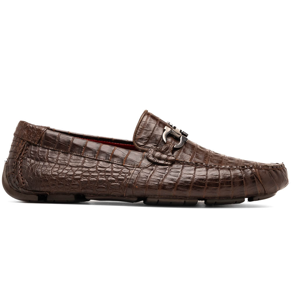The Marco Di Milano Parma Brown features a pair of brown caiman belly loafers with black metal buckles—one upright, the other on its side showing the sole—a luxurious footwear choice.