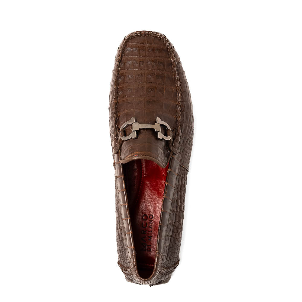 The Marco Di Milano Parma Brown features a pair of brown caiman belly loafers with black metal buckles—one upright, the other on its side showing the sole—a luxurious footwear choice.
