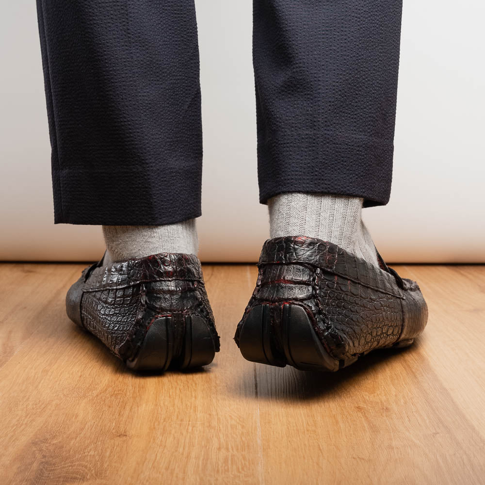 The Marco Di Milano Parma Blackcherry loafers feature genuine caiman leather with a crocodile pattern and metal buckle detail—luxury men's slip-ons shown upright and angled to display the sole, designed for effortless elegance.
