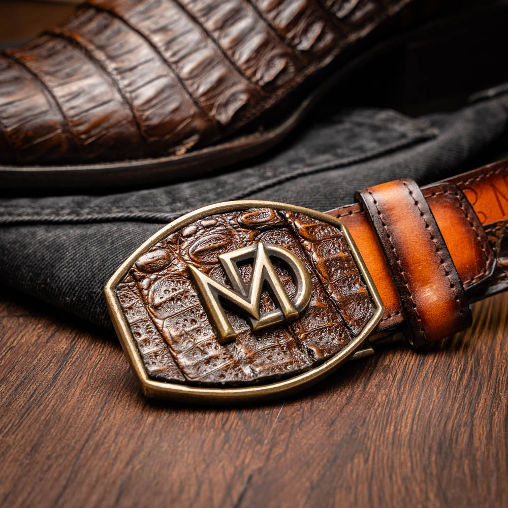 A pair of Marco Di Milano Phoenix Aged Brown men's boots, one upright and one showing the sole, crafted from genuine caiman belly skin with a crocodile texture and detailed stitching—ideal for any Western collection.