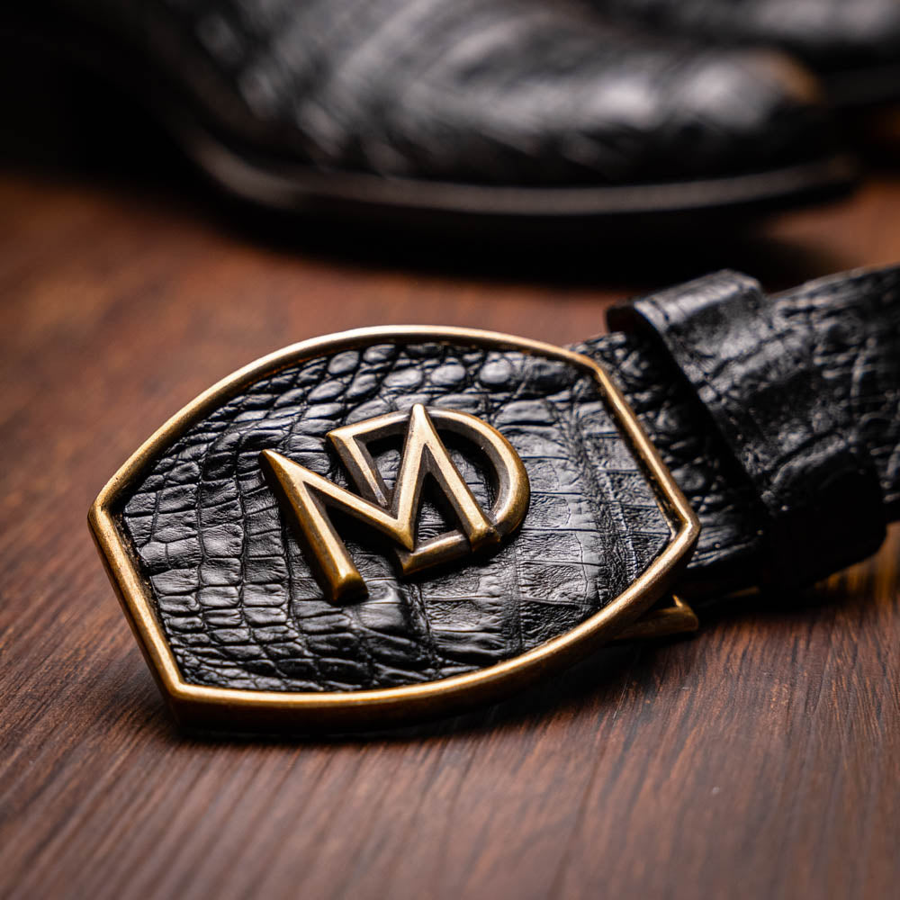 A pair of Phoenix Black Western cowboy boots by Marco Di Milano, one upright and one showing the sole, featuring a textured pattern and the brand name on the sole.