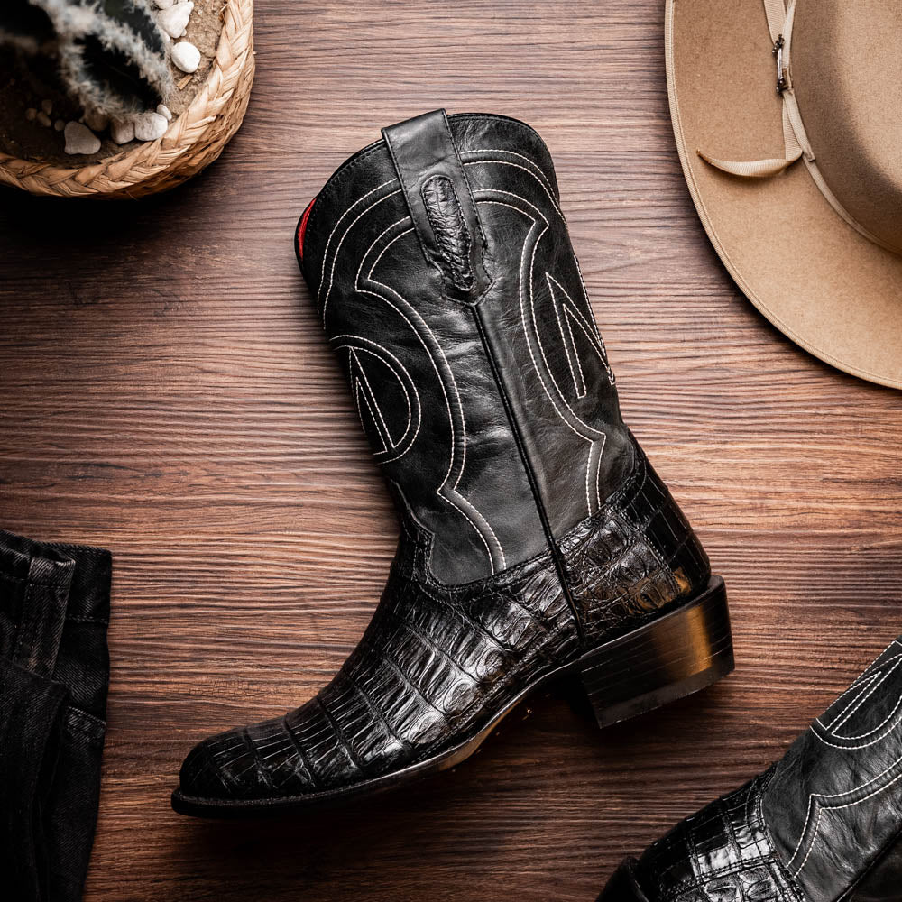 A pair of Phoenix Black Western cowboy boots by Marco Di Milano, one upright and one showing the sole, featuring a textured pattern and the brand name on the sole.