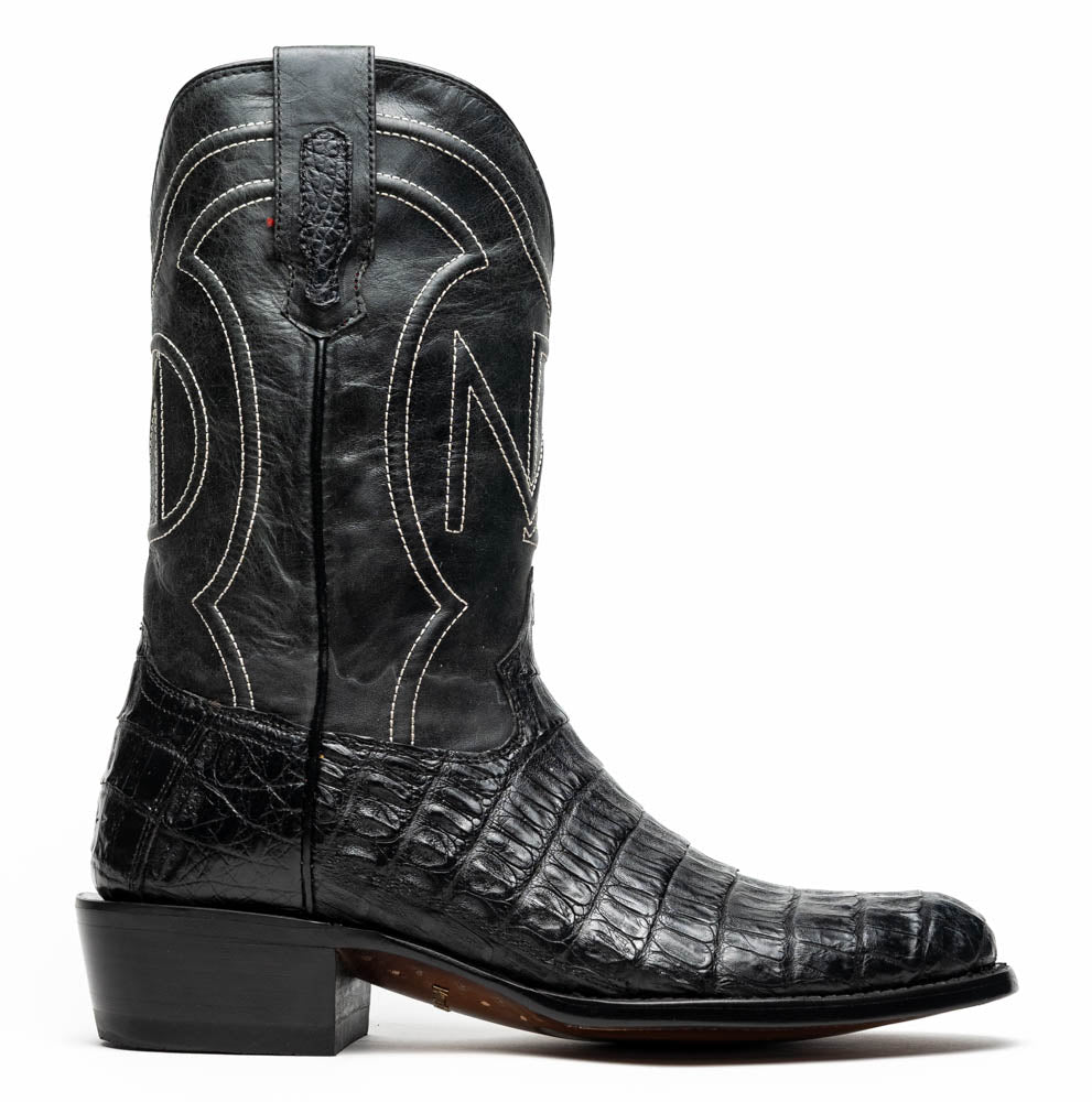 A pair of Phoenix Black Western cowboy boots by Marco Di Milano, one upright and one showing the sole, featuring a textured pattern and the brand name on the sole.