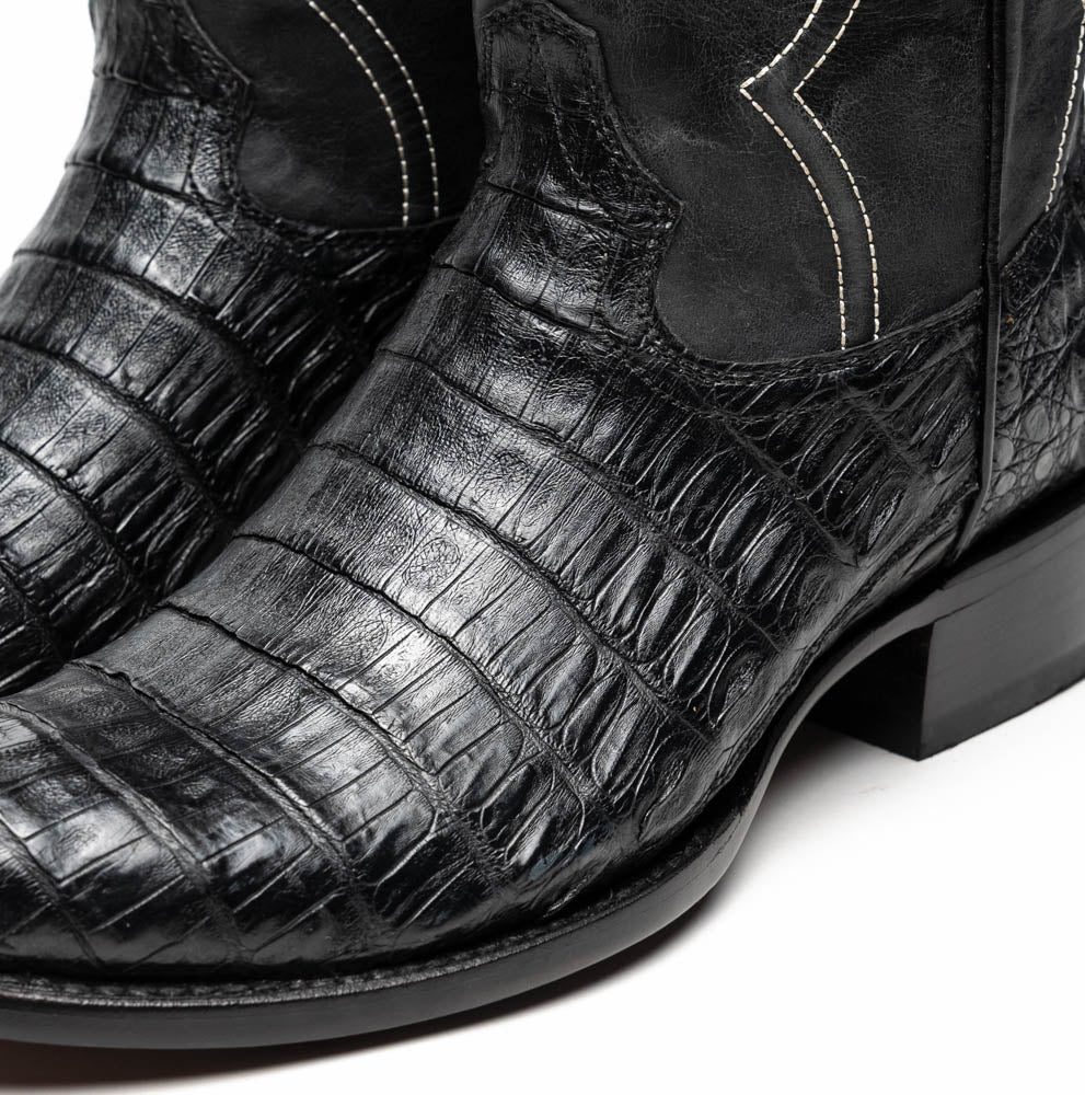 A pair of Phoenix Black Western cowboy boots by Marco Di Milano, one upright and one showing the sole, featuring a textured pattern and the brand name on the sole.