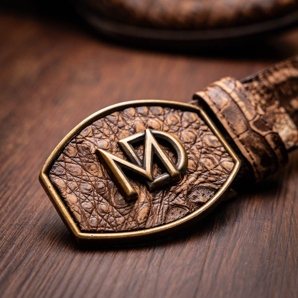 The Phoenix Stone Brown by Marco Di Milano are brown Western cowboy boots featuring crocodile-patterned textured leather, decorative stitching, and branded soles.