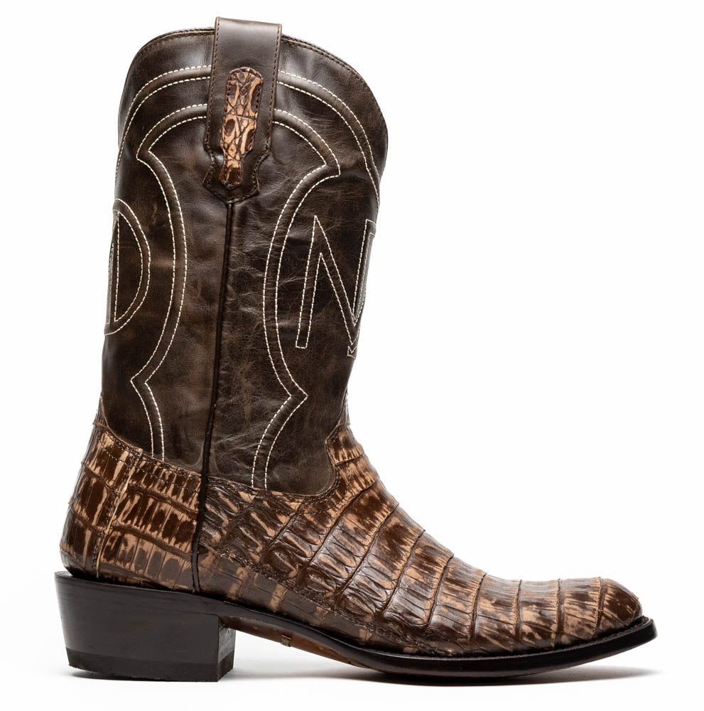 The Phoenix Stone Brown by Marco Di Milano are brown Western cowboy boots featuring crocodile-patterned textured leather, decorative stitching, and branded soles.