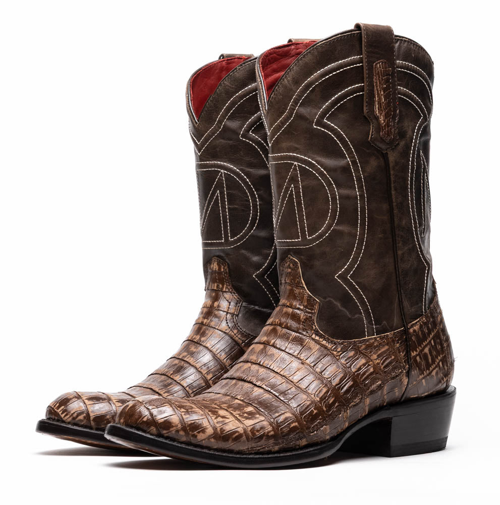 The Phoenix Stone Brown by Marco Di Milano are brown Western cowboy boots featuring crocodile-patterned textured leather, decorative stitching, and branded soles.