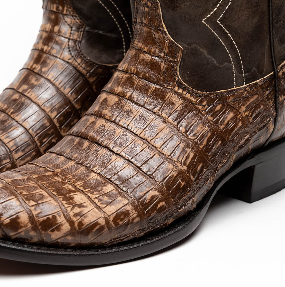The Phoenix Stone Brown by Marco Di Milano are brown Western cowboy boots featuring crocodile-patterned textured leather, decorative stitching, and branded soles.