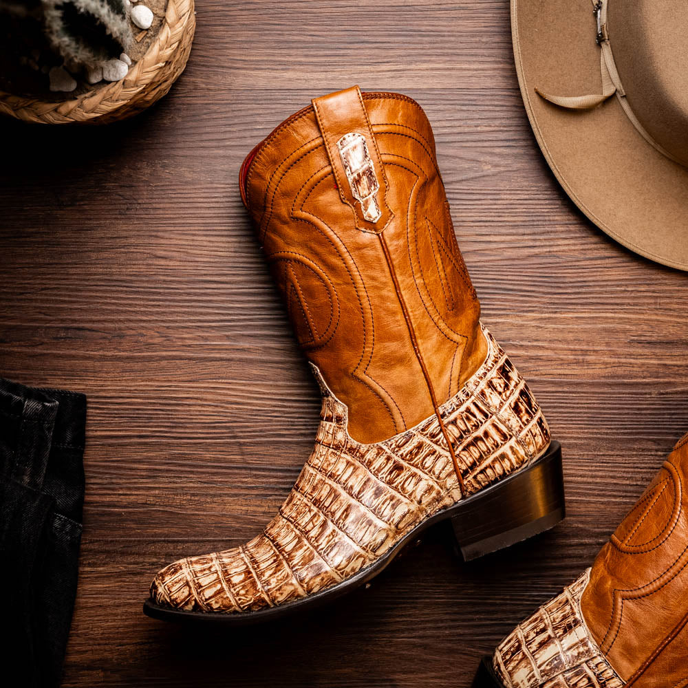 A pair of Phoenix Stone Orix brown Western cowboy boots by Marco Di Milano, featuring an alligator texture—one boot upright, the other displaying the sole with the brand logo.