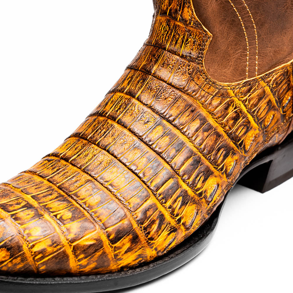 The Phoenix Mustard Brown by Marco Di Milano is a pair of Western boots in genuine caiman belly leather with a textured exotic finish and branded sole, shown against a white background.