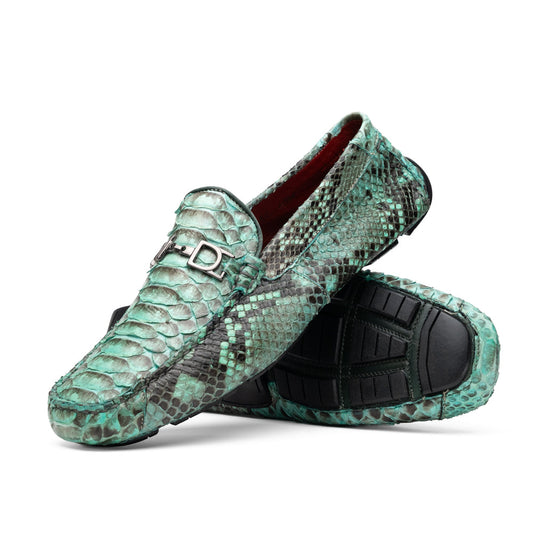 Introducing the Pia Aqua by Marco Di Milano—a pair of luxury men’s loafers handcrafted from striking green python skin. Featuring black rubber soles and silver buckle accents, one shoe is elegantly displayed on its side to highlight the distinctive design of this opulent driver shoe.