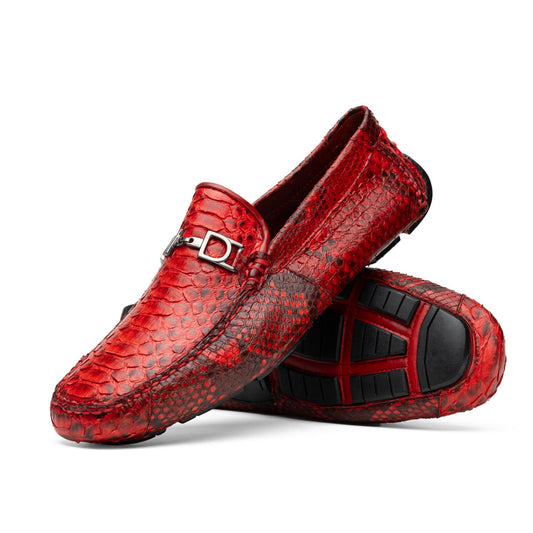 A pair of Pia Red loafers by Marco Di Milano—crafted as luxury men’s driver shoes in a striking red snakeskin pattern, featuring black rubber soles and silver buckle detailing, with one shoe upright and the other displayed on its side—showcase the allure of exotic python-inspired style in a distinguished design.