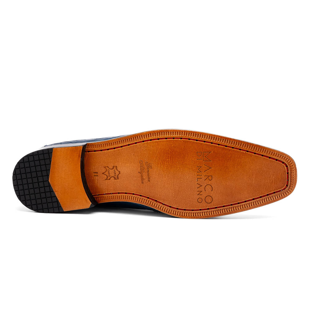 The Marco Di Milano "Pietro Blue Jeans" are luxury men's lace-up boots in blue crocodile-pattern leather, with one standing upright and the other tilted to reveal the tan embossed sole.