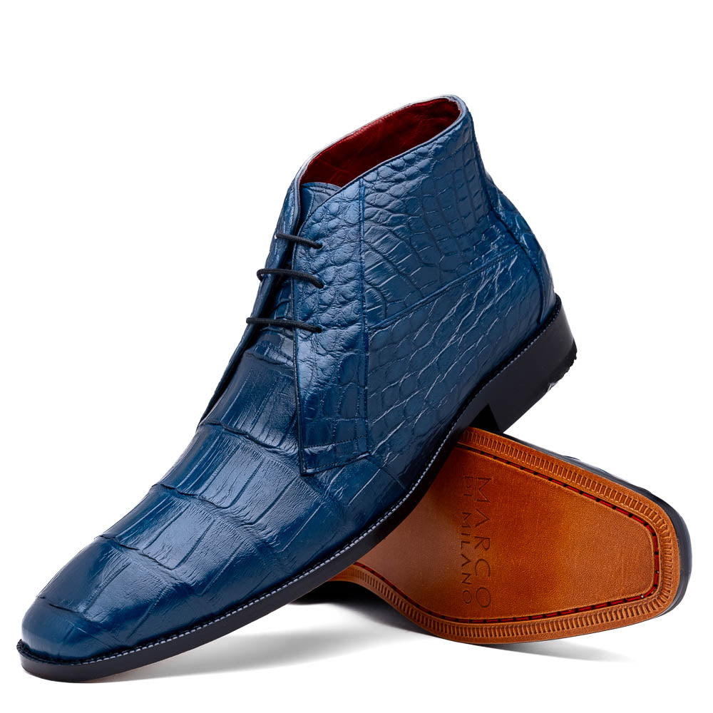 The Marco Di Milano "Pietro Blue Jeans" are luxury men's lace-up boots in blue crocodile-pattern leather, with one standing upright and the other tilted to reveal the tan embossed sole.