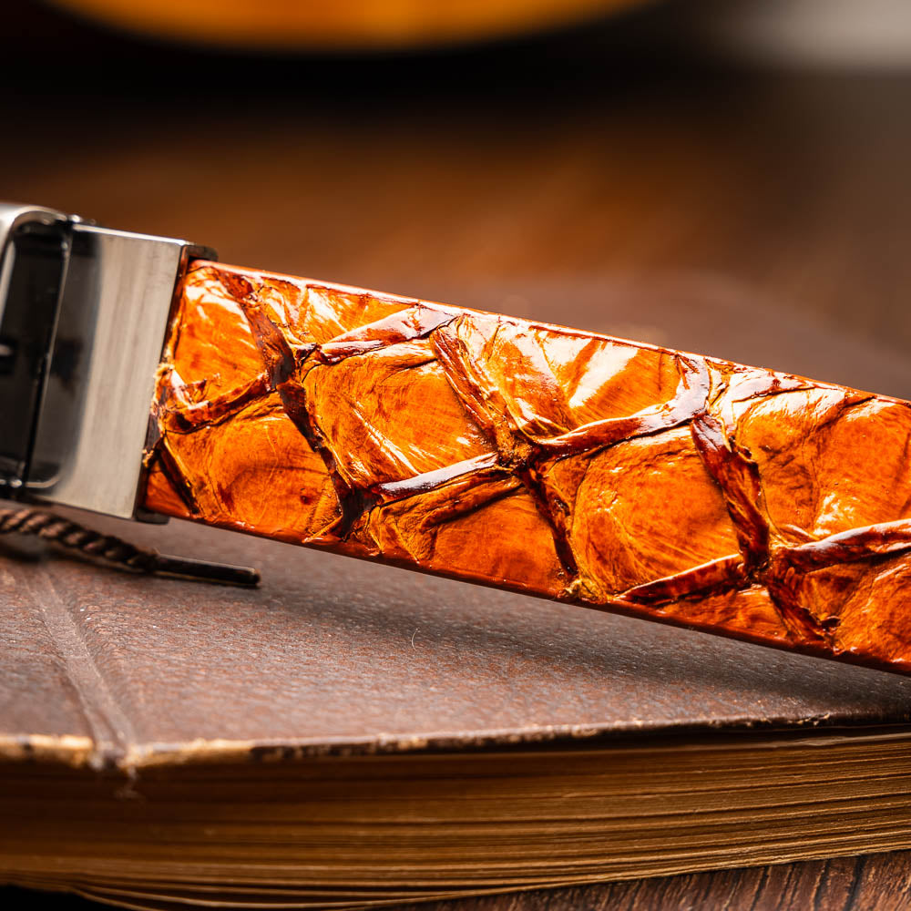 The Olivieri Belt Brandy by Marco Di Milano features brown textured genuine pirarucu leather and a silver buckle engraved with the brand's logo, coiled neatly against a white background.