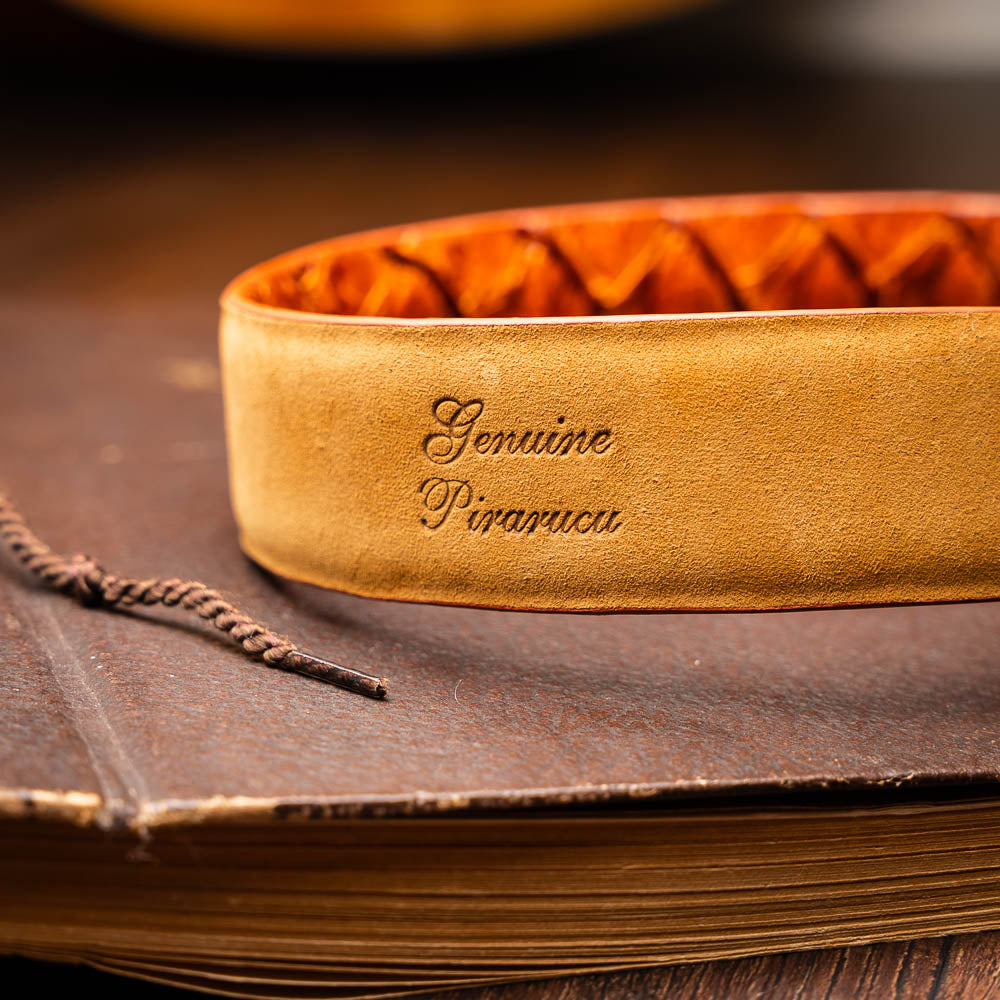 The Olivieri Belt Brandy by Marco Di Milano features brown textured genuine pirarucu leather and a silver buckle engraved with the brand's logo, coiled neatly against a white background.