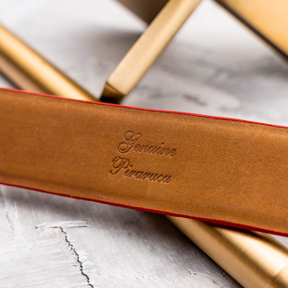 The Olivieri Belt Red by Marco Di Milano features textured genuine pirarucu leather and a metallic buckle with engraved branding, coiled on a white background—a signature accessory from this renowned luxury brand.