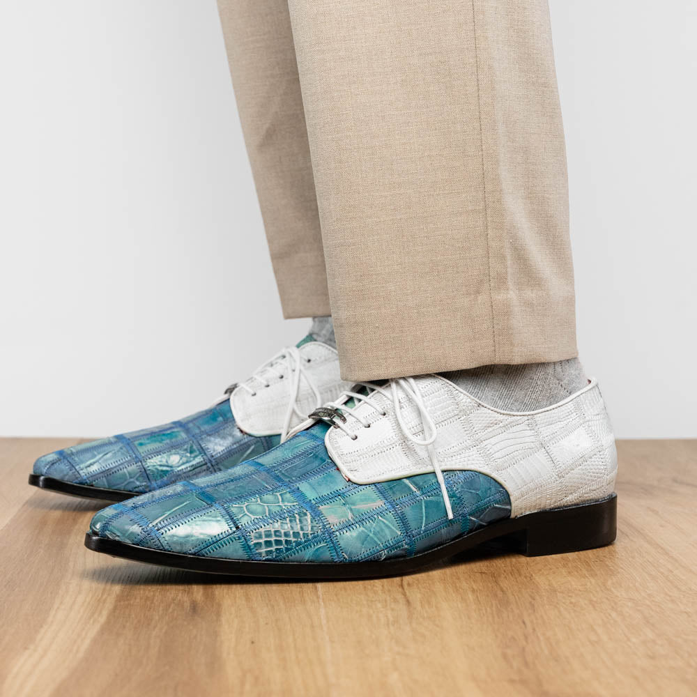 The "Pissa Aqua/White" by Marco Di Milano is a men's dress shoe with a white textured upper, teal blue patterned lower, hand-painted finishes, white laces, and a black sole—showcasing luxury style and craftsmanship.