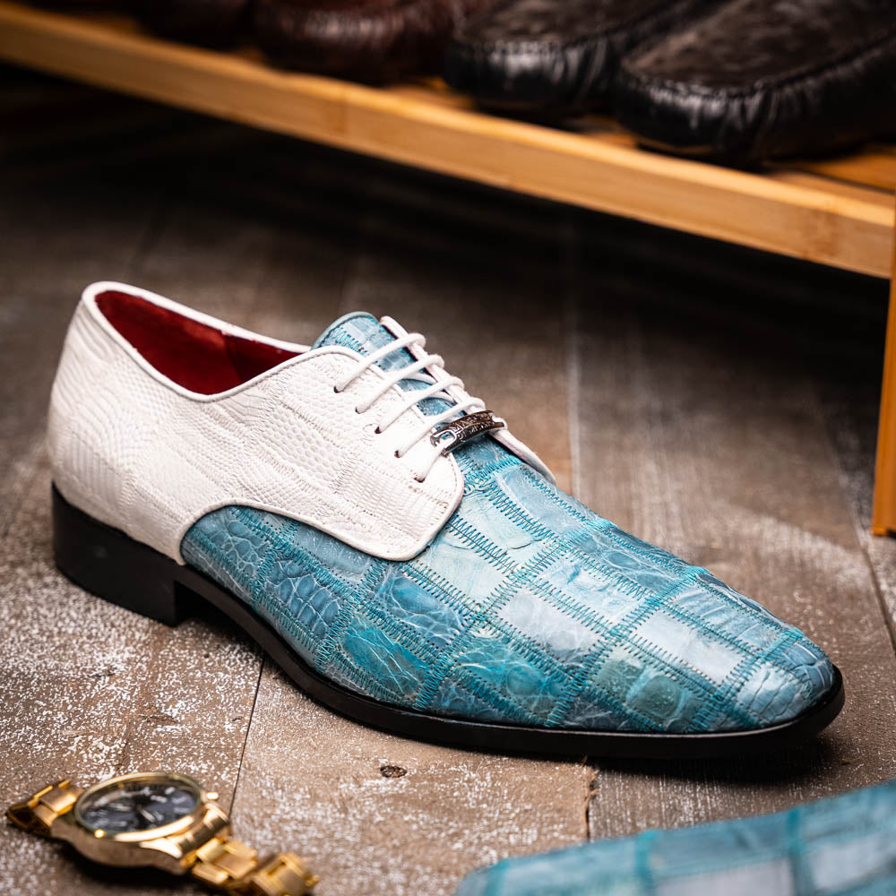 The "Pissa Aqua/White" by Marco Di Milano is a men's dress shoe with a white textured upper, teal blue patterned lower, hand-painted finishes, white laces, and a black sole—showcasing luxury style and craftsmanship.