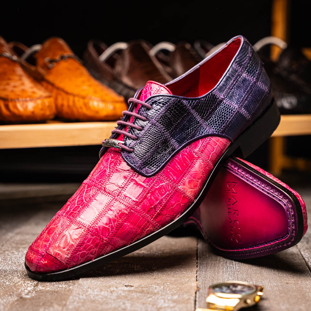 The Pissa Pink/Purple by Marco Di Milano are men's luxury dress shoes crafted from genuine exotics, featuring hand-painted pink and purple crocodile and lizard patterns—one shoe upright, the other on its side to display the sole.
