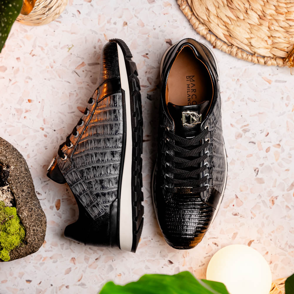 The Marco Di Milano Portici Gray / Black sneaker features black textured leather, black laces, and a white-trimmed rubber sole—one shoe upright and the other on its side—offering luxury footwear with a refined finish.