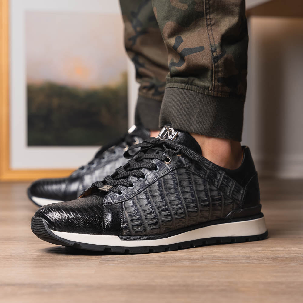The Marco Di Milano Portici Gray / Black sneaker features black textured leather, black laces, and a white-trimmed rubber sole—one shoe upright and the other on its side—offering luxury footwear with a refined finish.