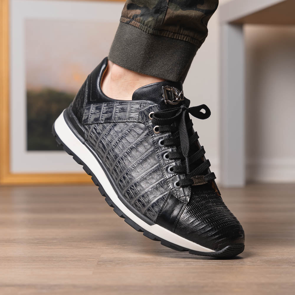 The Marco Di Milano Portici Gray / Black sneaker features black textured leather, black laces, and a white-trimmed rubber sole—one shoe upright and the other on its side—offering luxury footwear with a refined finish.