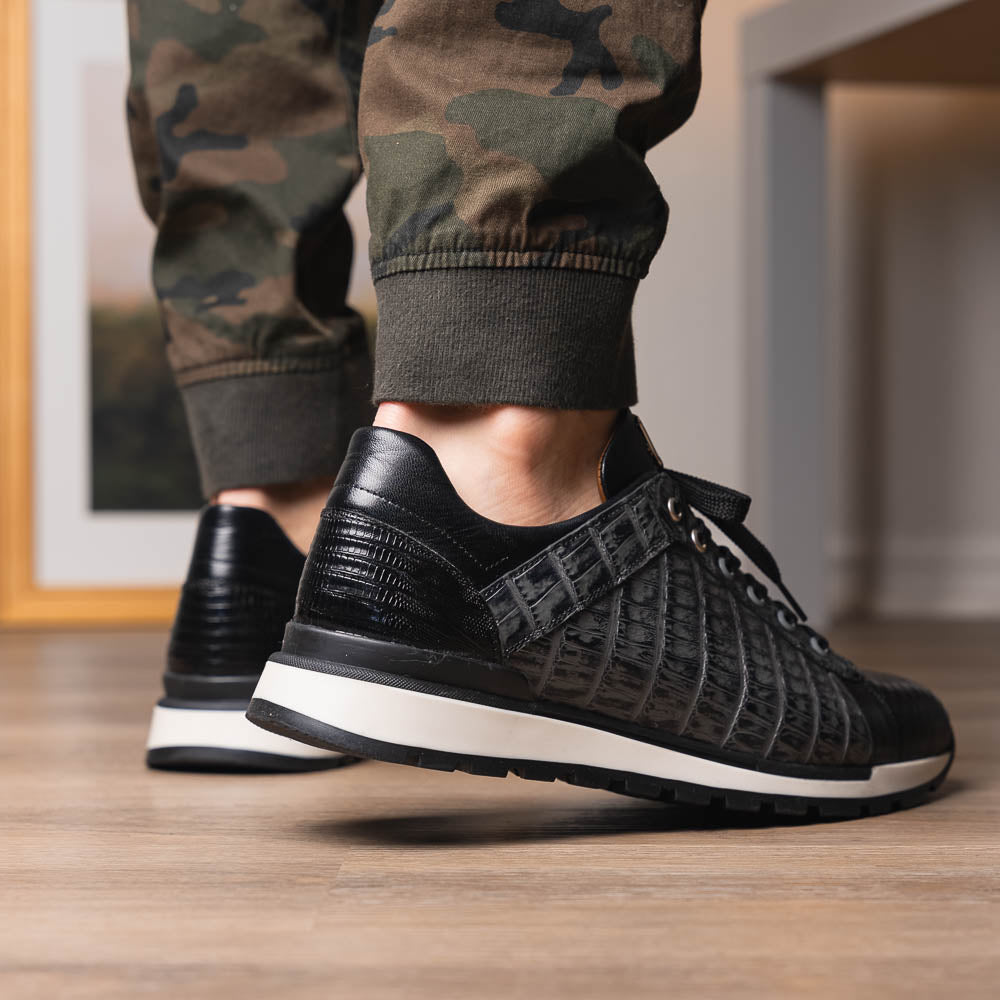 The Marco Di Milano Portici Gray / Black sneaker features black textured leather, black laces, and a white-trimmed rubber sole—one shoe upright and the other on its side—offering luxury footwear with a refined finish.