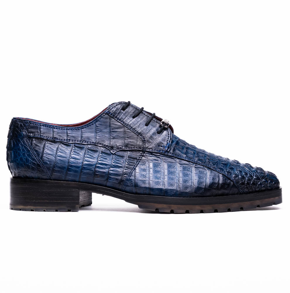 The Marco Di Milano Ragusa Stained Navy is a pair of luxury men's dress shoes in blue crocodile-patterned leather—one upright, one angled to display the sole—handcrafted for sophistication and timeless style.