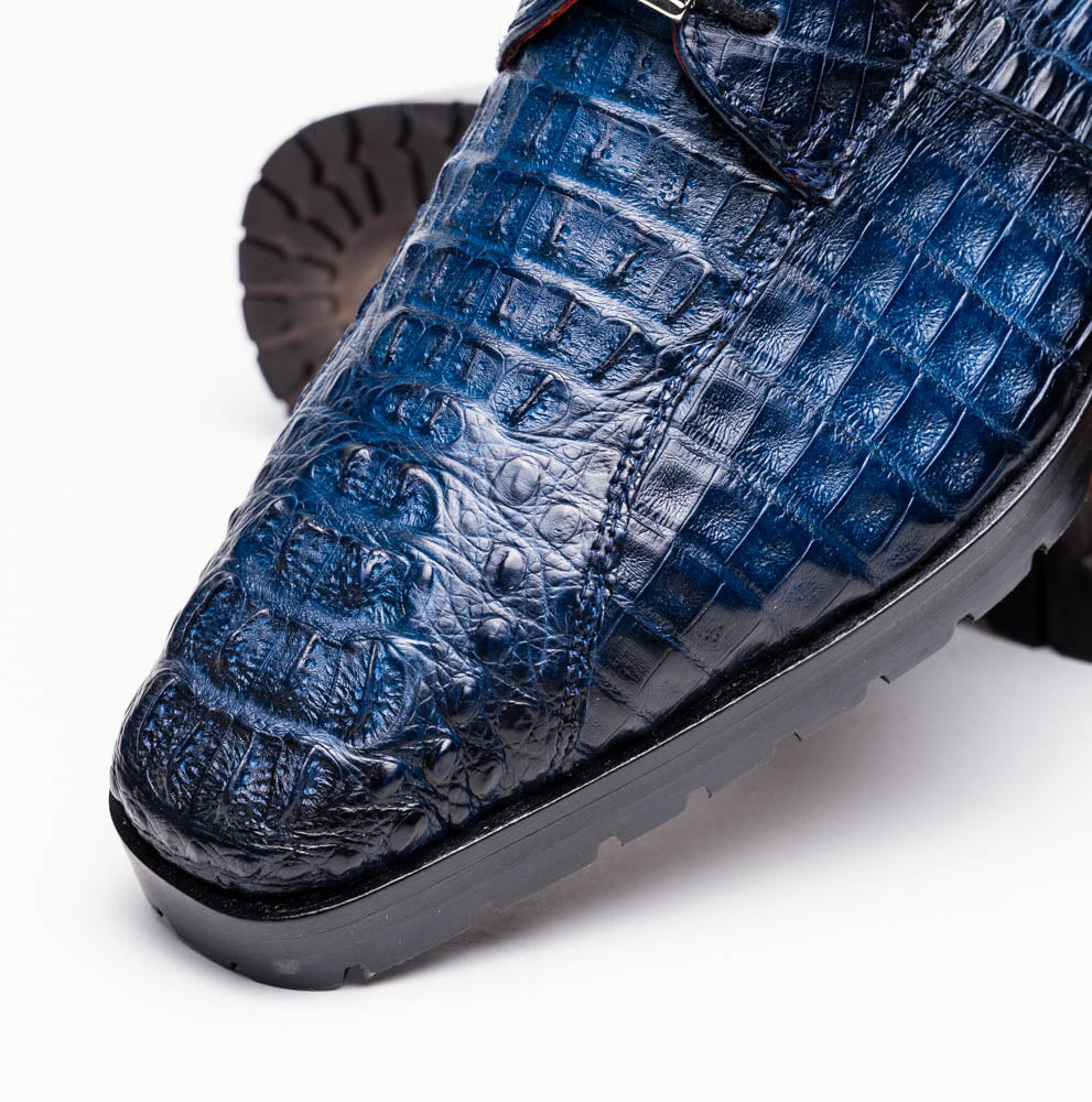 The Marco Di Milano Ragusa Stained Navy is a pair of luxury men's dress shoes in blue crocodile-patterned leather—one upright, one angled to display the sole—handcrafted for sophistication and timeless style.