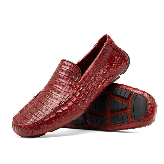 The Marco Di Milano Remo Wine features red crocodile-pattern leather driving shoes: one upright, one on its side showing a black rubber sole with red highlights—ideal for luxury men's footwear enthusiasts.