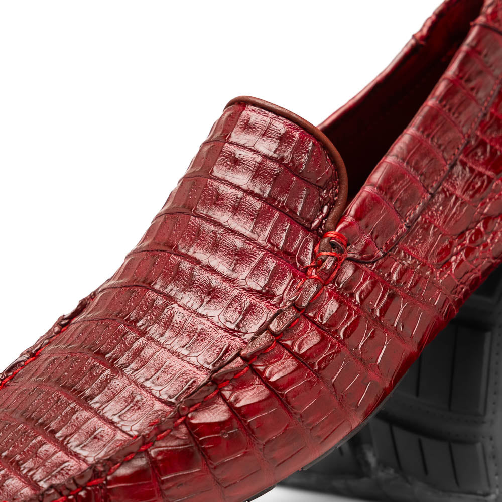 The Marco Di Milano Remo Wine features red crocodile-pattern leather driving shoes: one upright, one on its side showing a black rubber sole with red highlights—ideal for luxury men's footwear enthusiasts.