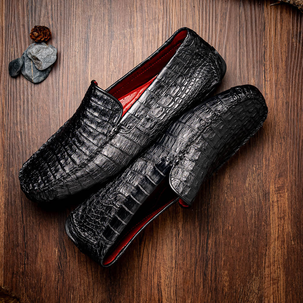 The Remo Black by Marco Di Milano: a pair of black textured driving loafers with a crocodile pattern—one upright, one showing the sole—making a bold statement in luxury men's footwear.