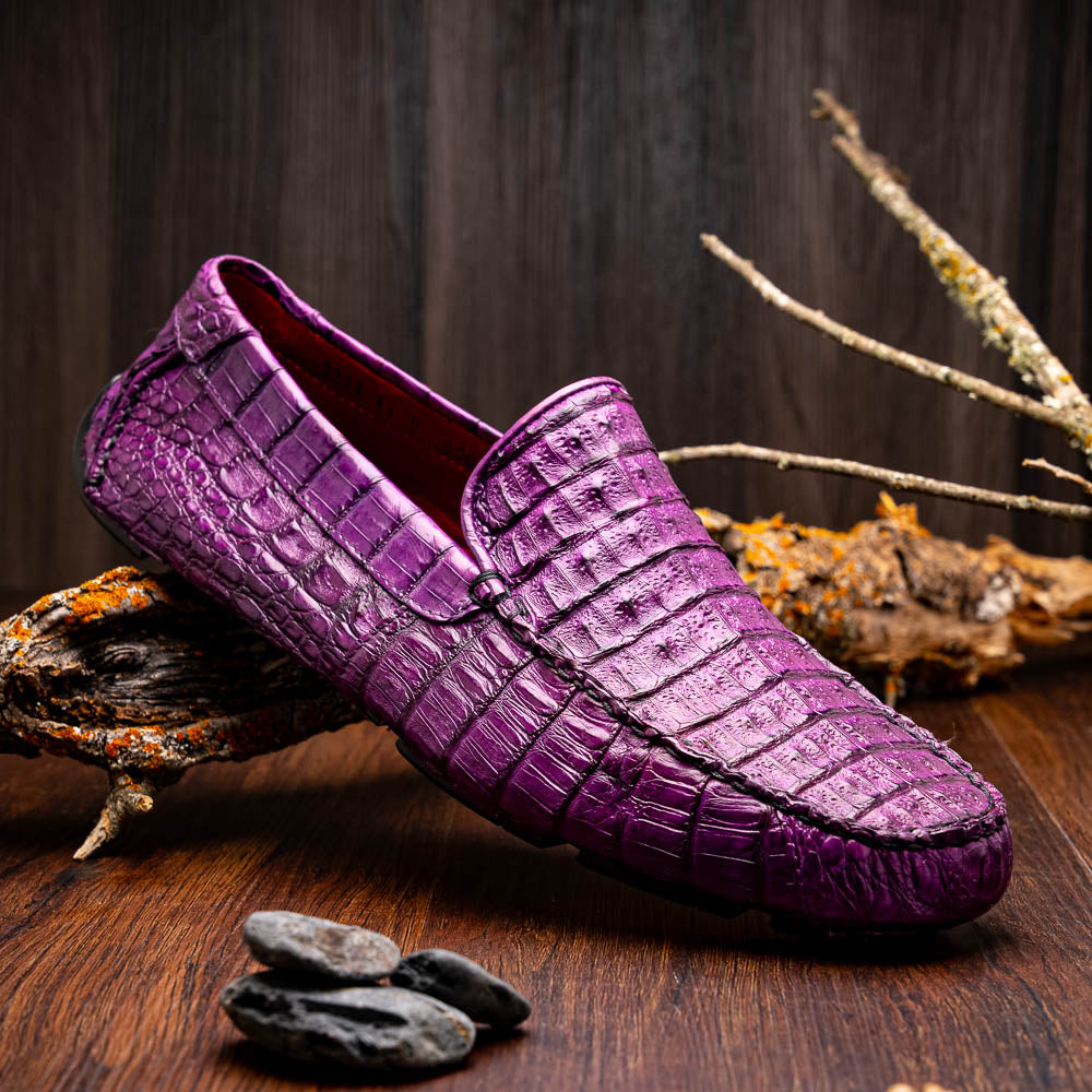 The Remo Purple by Marco Di Milano: a pair of crocodile-patterned purple leather driving loafers, one upright and one on its side revealing the black rubber sole—luxury men's footwear at its finest.