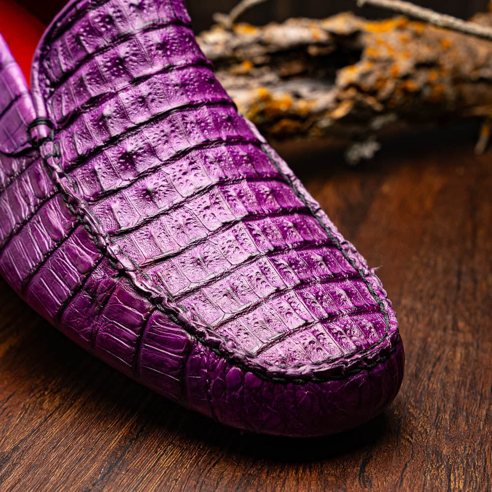 The Remo Purple by Marco Di Milano: a pair of crocodile-patterned purple leather driving loafers, one upright and one on its side revealing the black rubber sole—luxury men's footwear at its finest.