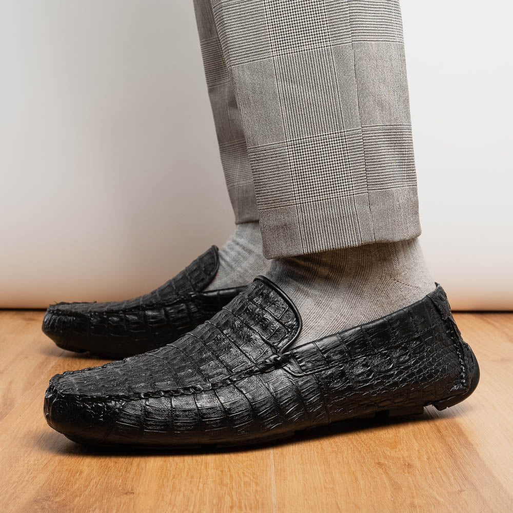 The Remo Black by Marco Di Milano: a pair of black textured driving loafers with a crocodile pattern—one upright, one showing the sole—making a bold statement in luxury men's footwear.