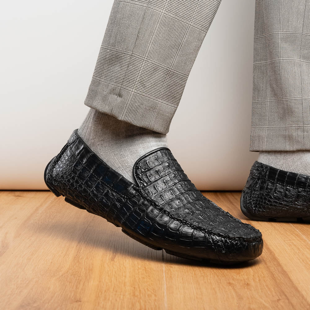 The Remo Black by Marco Di Milano: a pair of black textured driving loafers with a crocodile pattern—one upright, one showing the sole—making a bold statement in luxury men's footwear.