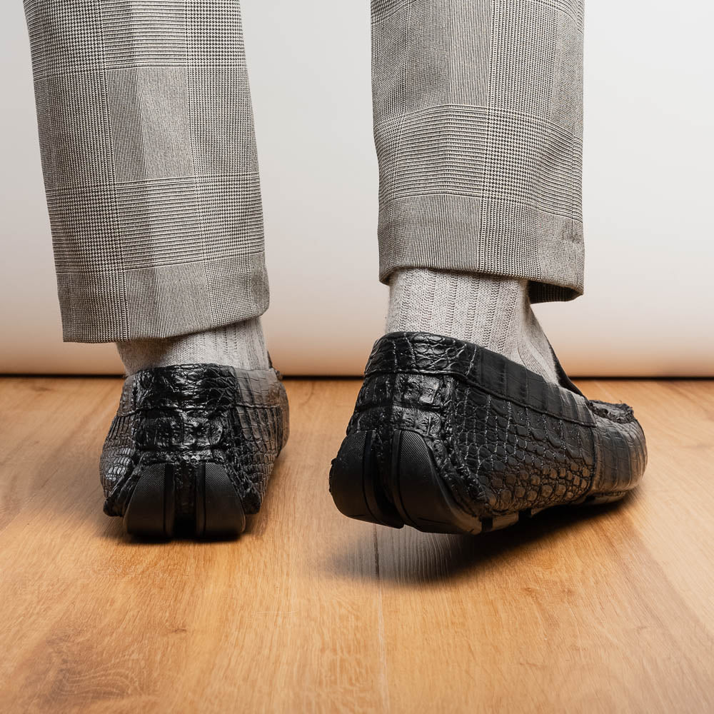 The Remo Black by Marco Di Milano: a pair of black textured driving loafers with a crocodile pattern—one upright, one showing the sole—making a bold statement in luxury men's footwear.