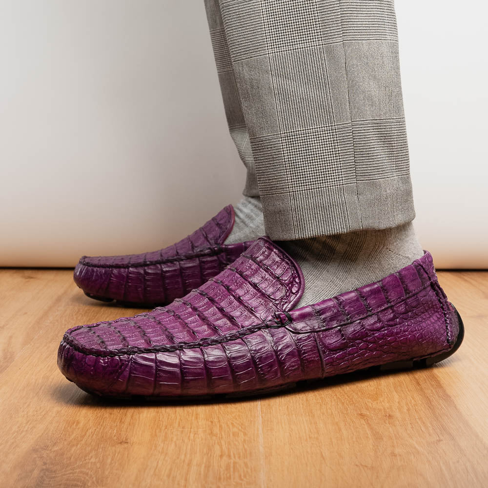 The Remo Purple by Marco Di Milano: a pair of crocodile-patterned purple leather driving loafers, one upright and one on its side revealing the black rubber sole—luxury men's footwear at its finest.