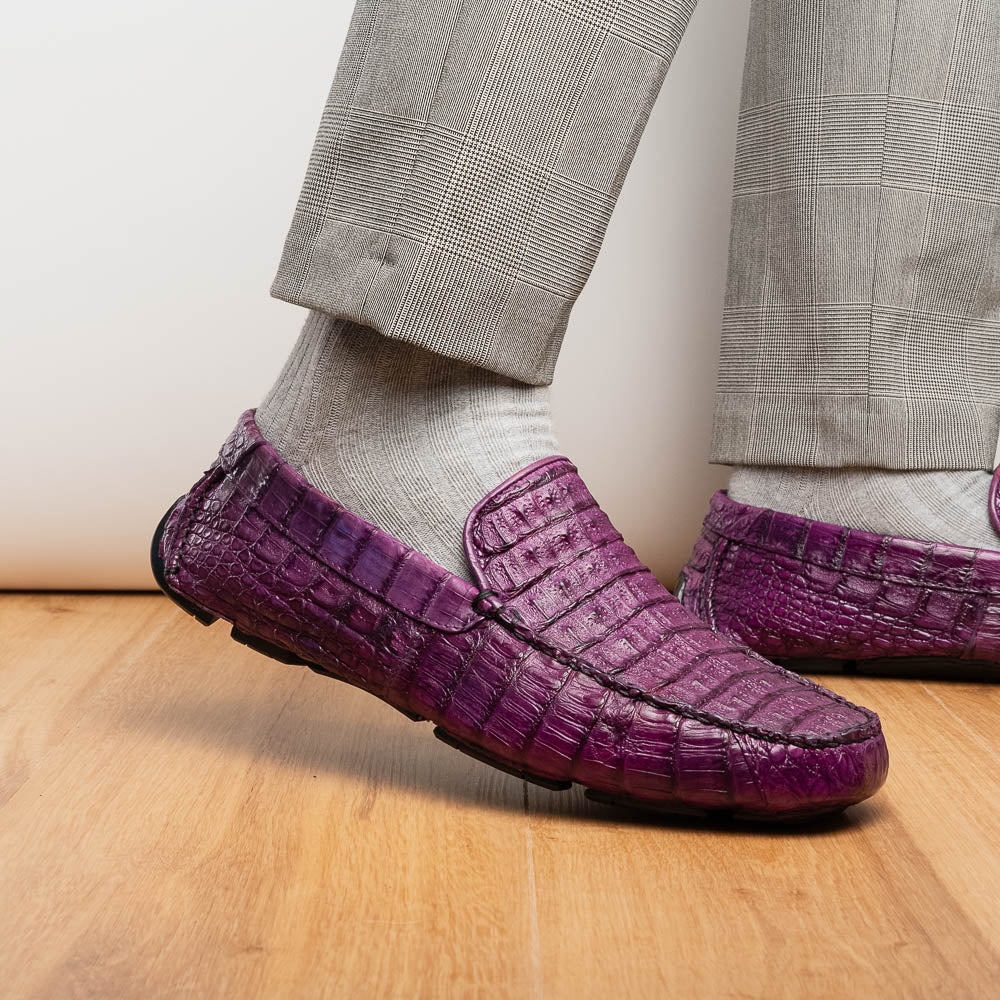 The Remo Purple by Marco Di Milano: a pair of crocodile-patterned purple leather driving loafers, one upright and one on its side revealing the black rubber sole—luxury men's footwear at its finest.
