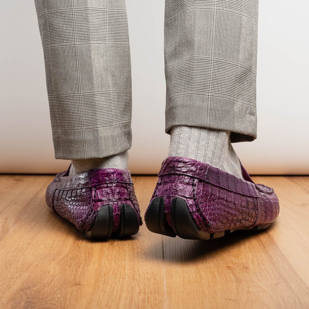 The Remo Purple by Marco Di Milano: a pair of crocodile-patterned purple leather driving loafers, one upright and one on its side revealing the black rubber sole—luxury men's footwear at its finest.