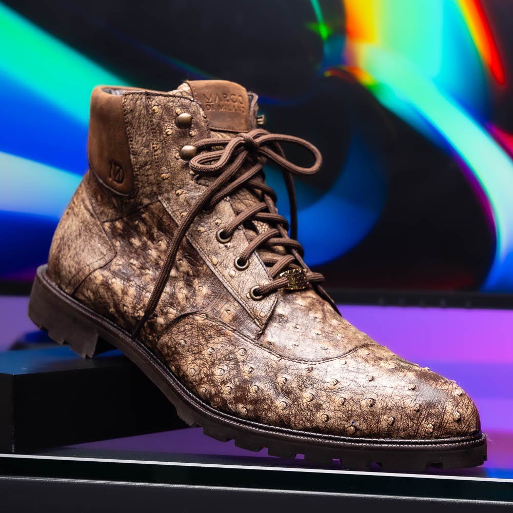 The Renzo Stone Brown by Marco Di Milano are lace-up ankle boots featuring a textured, speckled pattern and thick black rubber soles—one stands upright while the other lies on its side—ideal for luxury footwear lovers.